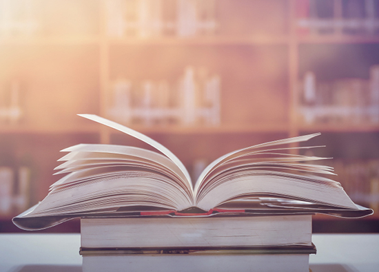 Open book atop stacked books.